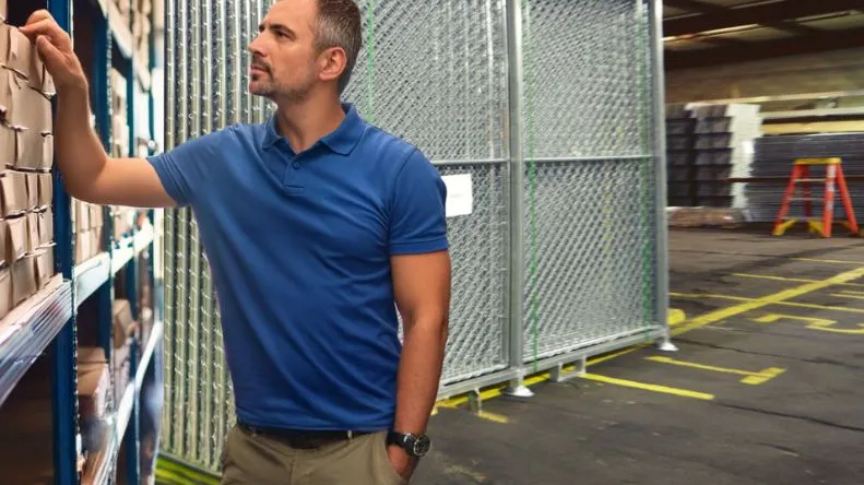 Site services specialist reviewing inventory beside chain-link temporary fence panels